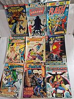 Photo of nine vintage comics laid out in three rows with titles from Marvel and DC including Spider-Man, Justice League of America, Flash, Lois Lane, Superman, The Phantom, and Marvel Team-Up