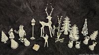 Full lot arrangement showing various clear glass Christmas trees, reindeer, snowmen, and other decorative figurines on a black background.