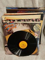 Vinyl records stacked with Razzy Bailey album visible open with vinyl record out of sleeve.