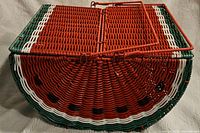 Side view showing woven basket mimicking a watermelon slice with red, green, white colors and black seeds.