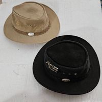 Pair of two Aussie Chiller Australian styled hats on a white surface, showing both black and tan hats.