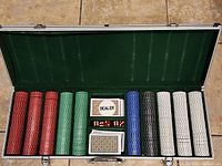 Poker set in aluminum case arranged with poker chips, cards, dice, and dealer marker card.