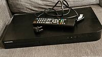 Samsung 3D Blu-Ray player with remote and power cord on fabric surface