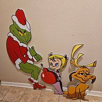 Full set of three Grinch-themed Christmas cutouts against wall, including The Grinch, Cindy Lou Who and Max