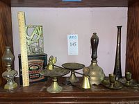 Full view of lot on shelf showing hunting horn, brass decor, miniature oil lamp and mustard tin