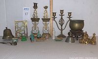Front view of assortment showing brass bell, trivet, candlesticks, porcelain figurines, jade items and gold-tone figurines
