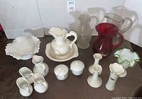 Wide group photo of all glassware and ceramics included in the lot showing pitchers, vases, bowl, candlesticks, and small creamers and sugars