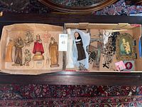 Top view photo of the entire assortment showing statues, rosaries, crucifixes, and framed religious image in cardboard boxes.