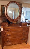 Full view of the walnut Victorian dresser with large oval mirror mounted in the center and two small valet boxes placed on top at each side.