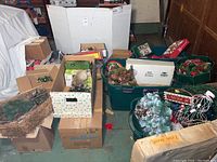 Multiple cardboard boxes and plastic bins containing wreaths, ornaments, figurines and lighting sets on floor