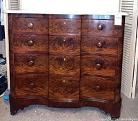 Front view of mahogany serpentine chest with marble top