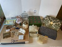 Full lot photo showing multiple vanity items including jewelry boxes, storage containers, and accessories on cardboard surface.