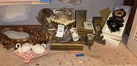 Full overview of assorted vintage gold-colored bathroom decor items including mirror frame, pedestal mirror, Kleenex box cover, candle holders, and ornate case.