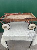 Full side view of vintage wooden pull wagon showing wooden bed, metal frame, wheels, and handle