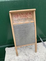 Front view of the antique Canuck Globe washboard showing corrugated metal scrubbing surface and logo text on wood upper panel