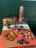 Full lot view showing silk butterfly tablecloth/shawl, brass candlesticks, decorative ewer, napkin rings, and vintage mirror