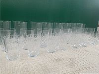 Crystal tumblers and glasses arranged in rows showing different cut patterns and varying heights.