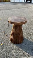 Full view of the faux wood pedestal table showing fluted column base and round top with wood grain pattern and cracks.