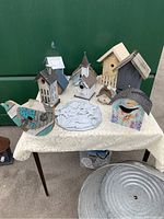 Photo showing all birdhouses arranged on a table with washtub planter and wall plaque