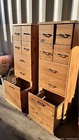 Photo showing two tall wooden office storage units side by side with multi small drawers at the top and open large filing cabinet drawers at the bottom.