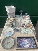 Wide view of wooden basket and various ceramic items including plates, trays, bowls, and flower models arranged on table
