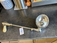 Full view of classic car spotlight showing the entire arm, spotlight head, and ivory handle on kitchen countertop.