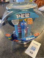 Front view of the clear plastic fishbowl case holding three PEZ dispensers with Finding Nemo and friends character heads visible.