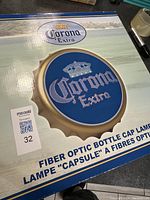 Photo of the original cardboard box packaging showing the Corona Extra fiber optic bottle cap lamp with product name and clear branding.