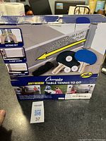 Box showing Champion Anywhere Table Tennis to Go kit with images and description of net extension, clamps, and play instructions.