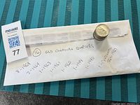 Stack and envelope of 16 old Canadian quarters with handwritten dates.