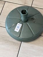 Top down view of green plastic patio umbrella stand showing filling hole and central socket.