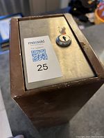 Close-up of the front side of metal lock box showing keyhole and surface wear.