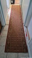 Full view of the 11ft antique floor runner rug laid out in a hallway, showing the intricate traditional pattern and color.