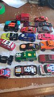 Top view of 20 assorted vintage Hot Wheels cars arranged on a surface, showing colors and models varying from sports to utility vehicles.