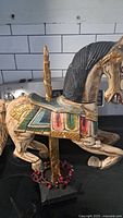 Side view of the wooden decorative horse showing colorful saddle and black mane against a tile kitchen backsplash.