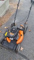 Front angle view of the orange Columbia gas lawn mower showing handlebar, engine cover with branding, wheels and deck