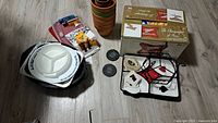 Full shot of all lot contents arranged on floor showing clay pots, foil pan, towels, sealers, coasters and boxed napkins or coasters.