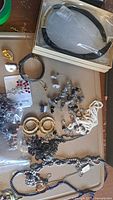 Various jewelry pieces together on a surface with headband in original box, earrings, bracelets, and necklaces present