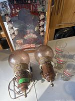Photo showing two Michelob plastic lights with textured round plastic light covers and wood bases with Michelob labels and eagle emblems, plus three Stroh's branded drinking glasses.