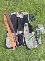 Full lot laid on grass showing vest, gloves, ammo belt, dual magazine holder, and handheld device