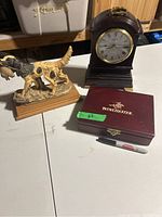 Overall photo showing the mantle clock, dog statue, and Winchester box on table with pen for scale.