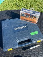 Blue plastic case with Mastercraft logo containing the tap and die set, next to the router bit set in clear plastic packaging with wooden holder.