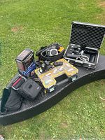 Overall lot arranged on outdoor bench showing bags, cases, cameras and accessories