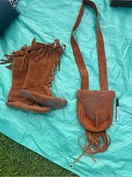 Photo showing side view of one moccasin boot and the fringe purse on a blue tarp.