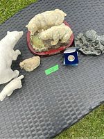 Photo showing several polar bear statues and other figurines on outdoor woven table surface with green grass background.