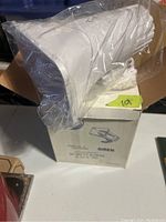 White electric siren in plastic bag with original cardboard box underneath.
