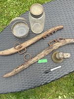 Vintage lot displayed on outdoor table: large Mason jar, glass bowl with metal handle, weathered wooden yoke with metal fittings, brass bell with leather handle, with Sharpie marker for scale.