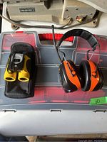 Lot items arranged on plastic organizer box: binoculars and hearing protection earmuffs