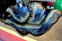 Photo of Mid Century Modern glazed stoneware bowl showing organic, wavy shape and blue-green glaze with brown and cream tones.