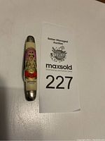 Top view of the pocket knife lying flat, showing the full image and text on the handle.